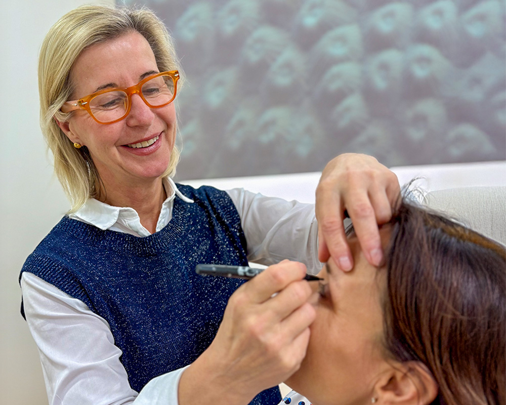 Dr. Dr. med. Susanne Herrmann-Frühwald demonstriert einen Schritt des Behandlungsverlaufs, indem sie behutsam die Stirn- und Augenpartie einer Patientin markiert. Die Ärztin arbeitet konzentriert und freundlich, um den Ablauf eines Faceliftings in der Sophienklinik Stuttgart anschaulich zu erklären.