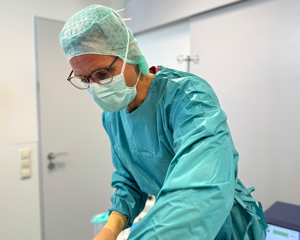 Dr. med. Konstantin Feise bereitet im OP-Bereich die nächsten Schritte einer Fettabsaugung (Liposuktion) vor. In steriler OP-Kleidung und mit ruhiger Konzentration arbeitet er präzise am Patienten – ein authentischer Einblick in den professionellen Behandlungsverlauf der Liposuktion in der Sophienklinik Stuttgart.